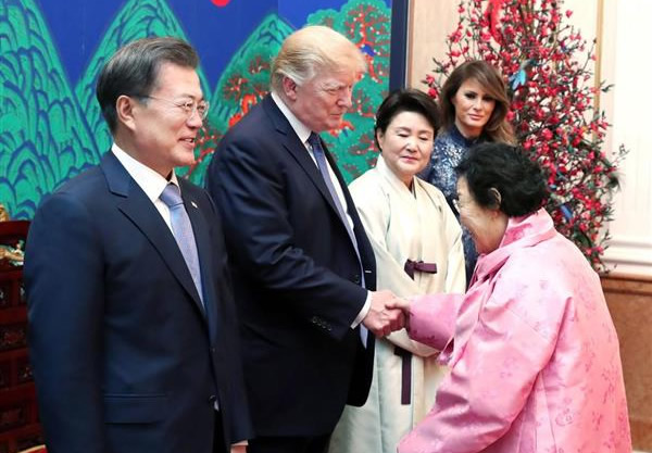 韓国大統領府での夕食会で握手するトランプ米大統領（中央）と元慰安婦とされる女性